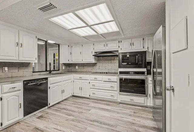 a kitchen with kitchen island white cabinets and stainless steel appliances