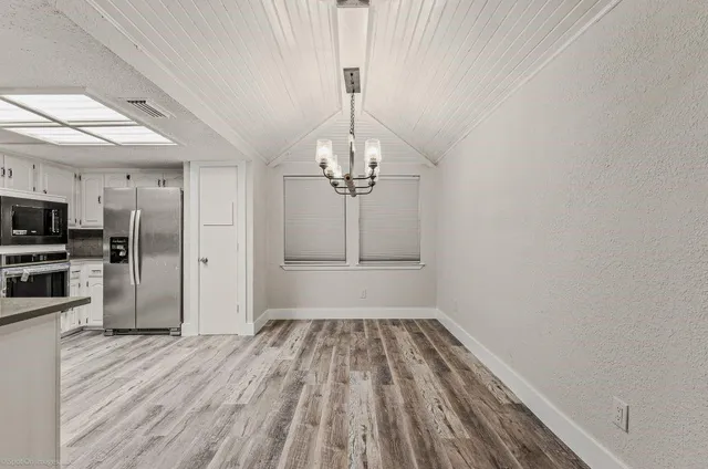 a view of a room with wooden floor electronic appliances and windows