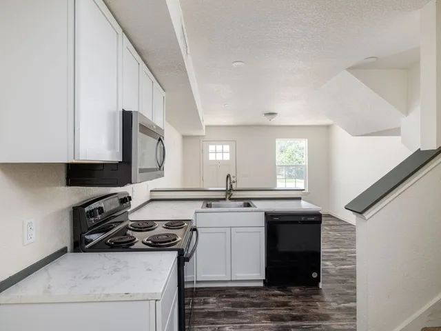 a kitchen with stainless steel appliances granite countertop a stove a sink and a microwave