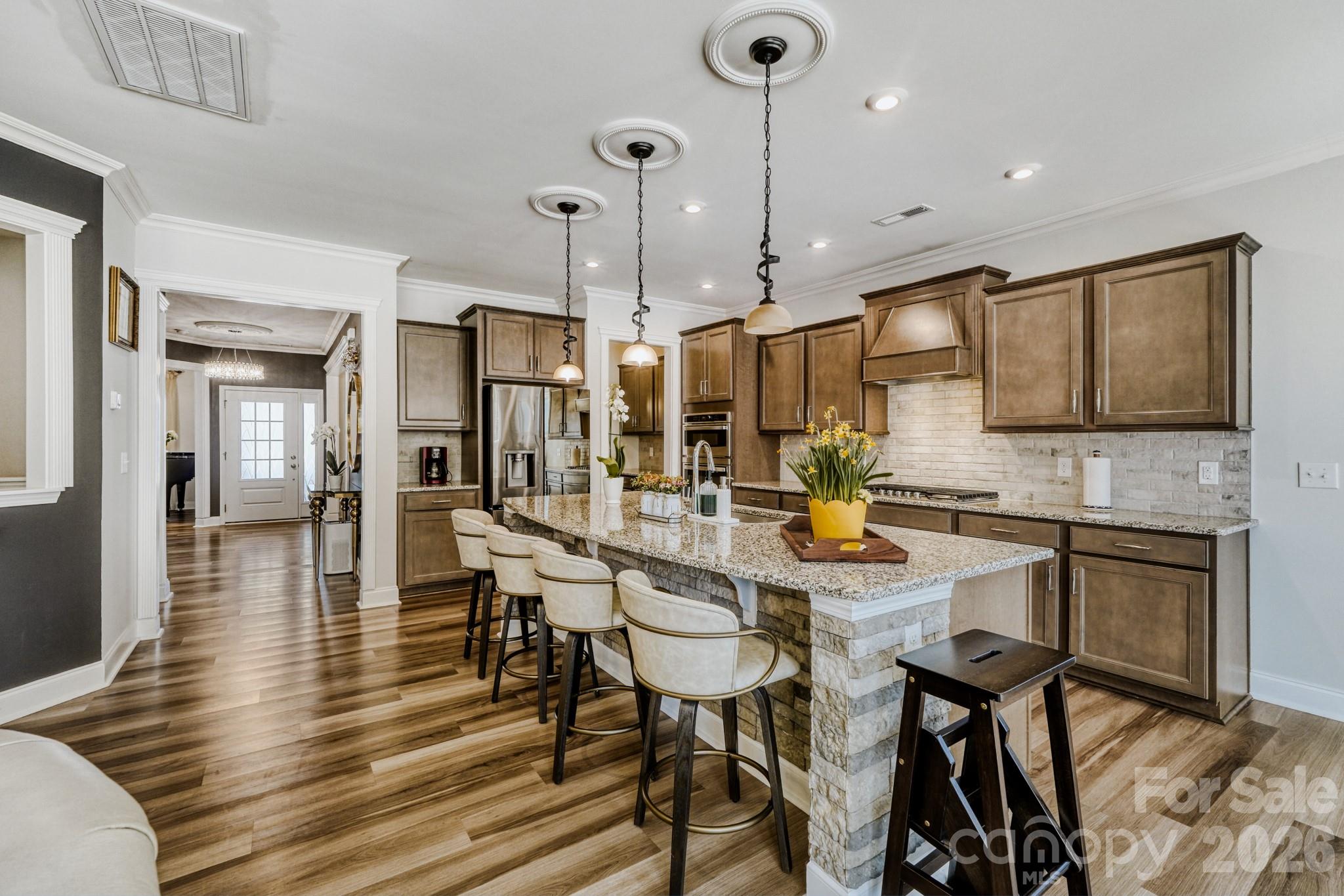 1318 Poppy Way Matthews, NC 28104 - Photo 12 of 33 a kitchen with stainless steel appliances kitchen island granite countertop a table chairs and a refrigerator