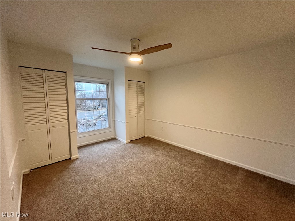 22701 Center Ridge Road, Unit 201 Rocky River, OH 44116 - Photo 26 of 37 Unfurnished bedroom with ceiling fan, dark carpet, and multiple closets