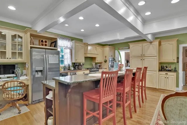 a kitchen with stainless steel appliances granite countertop a refrigerator a stove top oven and a dining table with wooden floor