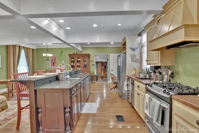 a kitchen with stainless steel appliances granite countertop a stove and a view of living room