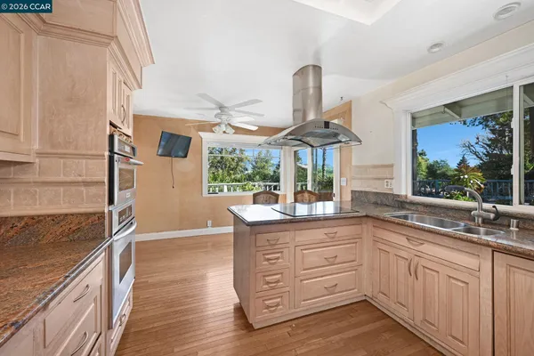a kitchen with stainless steel appliances granite countertop a sink a stove and a wooden floors