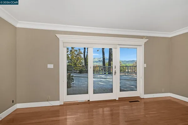 a view of an empty room with wooden floor and a window