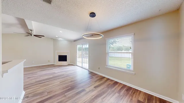 a view of an empty room with a window and wooden floor