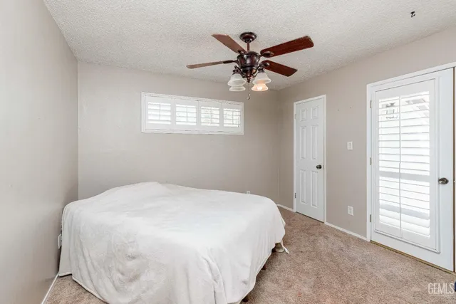a spacious bedroom with a bed and a flat tv screen on dresser