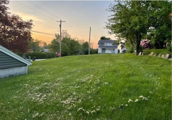 a view of a house with a big yard and large trees