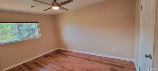 an empty room with a window and ceiling fan