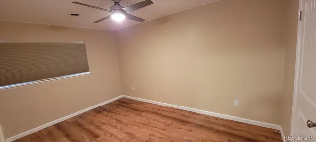 an empty room with a fan & a window