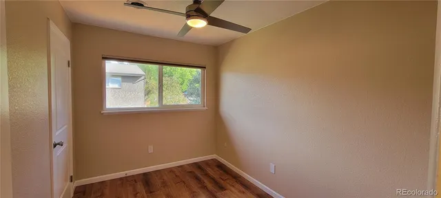 an empty room with a window and ceiling fan