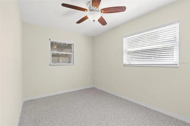 an empty room with a window and a fan