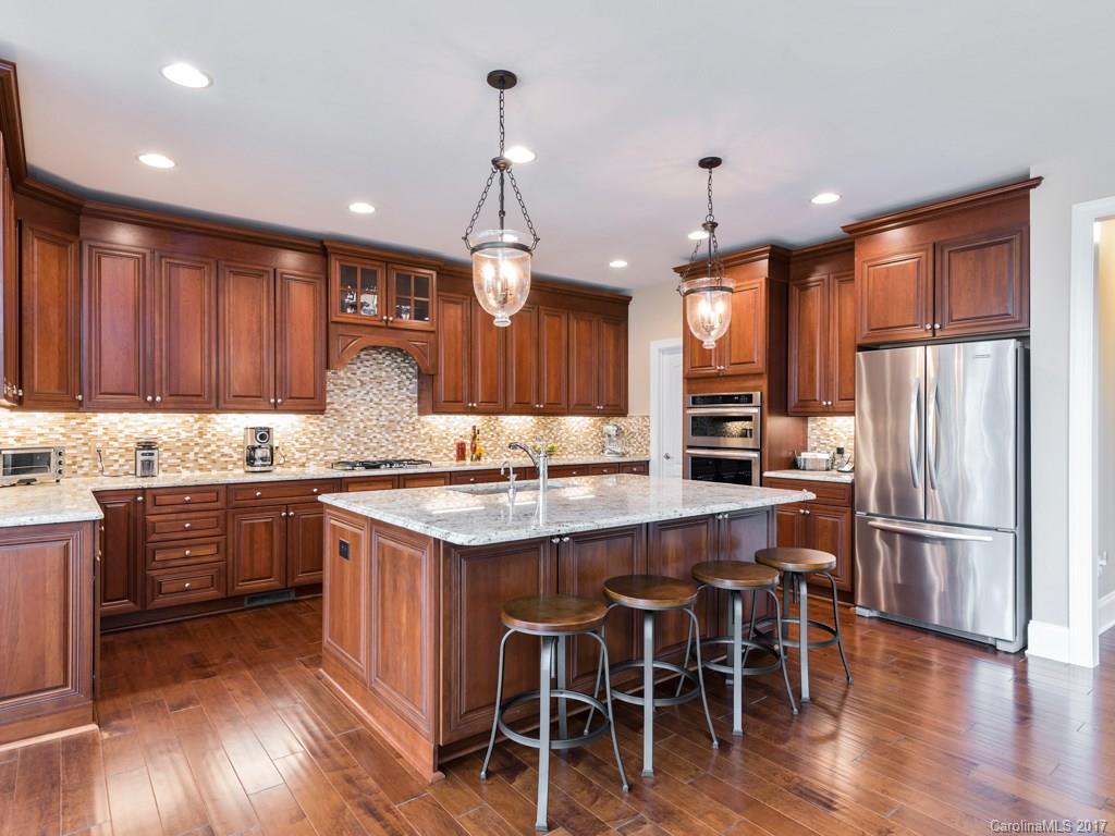 7005 Tea Olive Road Marvin, NC 28173 - Photo 4 of 24 a kitchen with stainless steel appliances granite countertop wooden floors stove and white cabinets