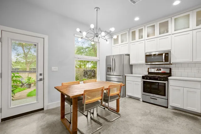 a kitchen that has a table chairs and stainless steel appliances