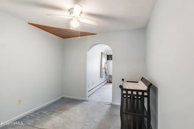 an empty room with chandelier fan and windows