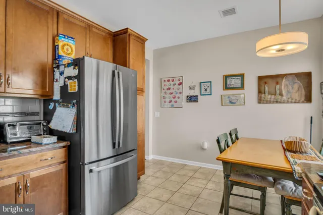 a kitchen with stainless steel appliances granite countertop a refrigerator a stove a sink and a dining table