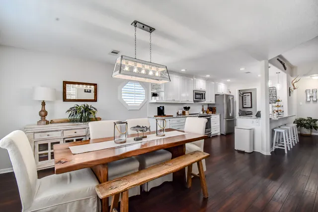 a view of a dining room and livingroom with furniture wooden floor a chandelier