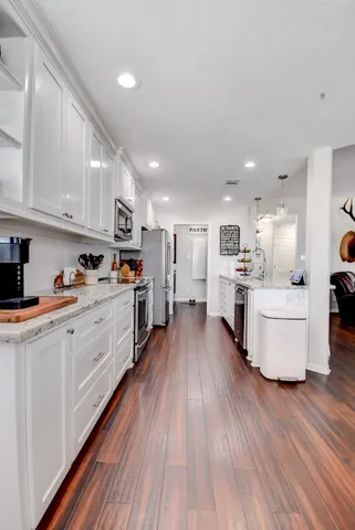 a large kitchen with stainless steel appliances lot of white cabinets and wooden floor