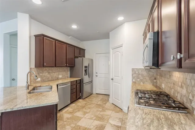 a kitchen with stainless steel appliances granite countertop a sink stove and refrigerator