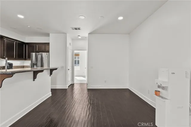 a view of a kitchen with a fridge and wooden floor