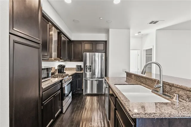 a kitchen with kitchen island granite countertop a sink stove refrigerator and cabinets