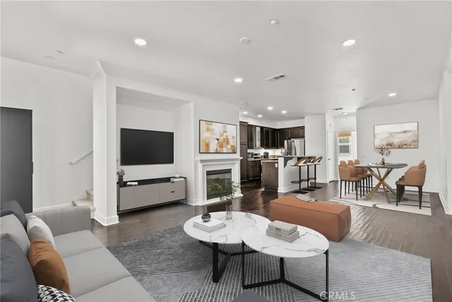 a living room with furniture a flat screen tv and kitchen view