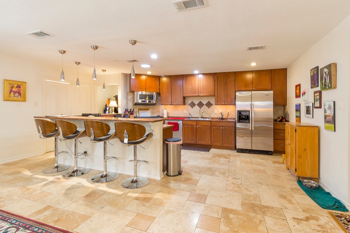 a kitchen with stainless steel appliances kitchen island granite countertop a refrigerator and a stove top oven