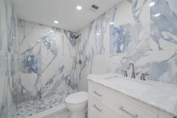 a bathroom with a granite countertop sink a toilet and a shower