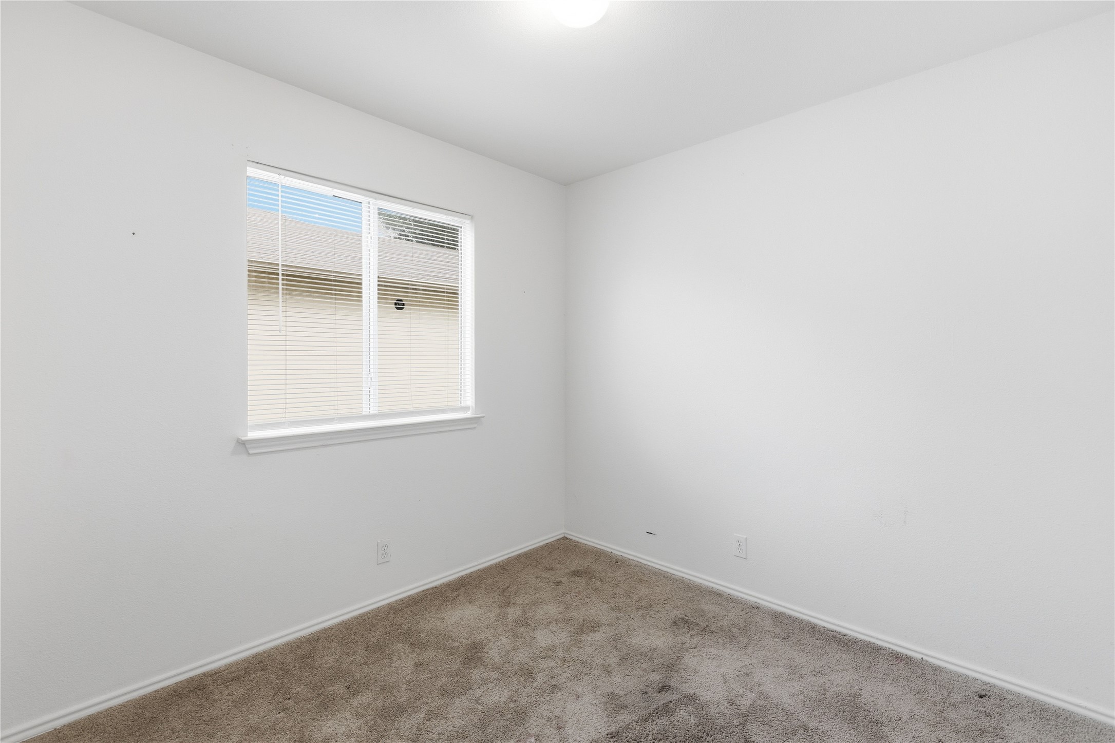 16112 Hamilton Point Circle Manor, TX 78653 - Photo 10 of 27 Neutral white walls with a single window featuring horizontal blinds