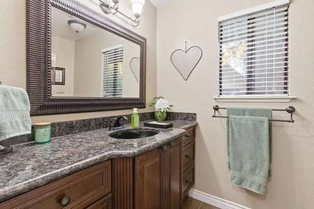 a bathroom with a granite countertop sink and a mirror