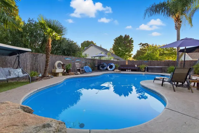 a view of a swimming pool with lawn chairs under an umbrella