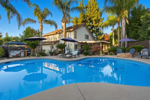 a view of a house with pool and chairs
