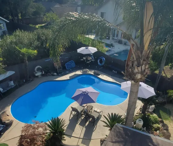 a view of a swimming pool with lawn chairs under an umbrella