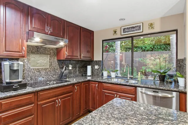 a kitchen with stainless steel appliances kitchen island granite countertop a sink window and cabinets
