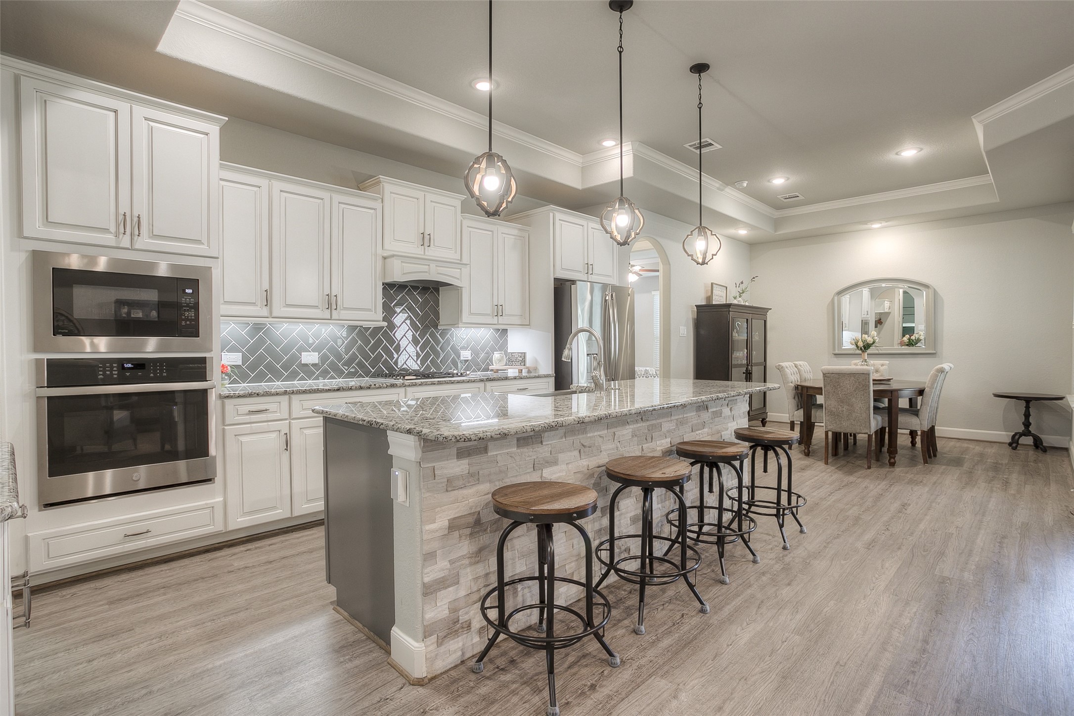 5757 Lakeside Villas Court Conroe, TX 77304 - Photo 5 of 50 a kitchen with stainless steel appliances kitchen island granite countertop a stove a sink a refrigerator and a dining table with wooden floor