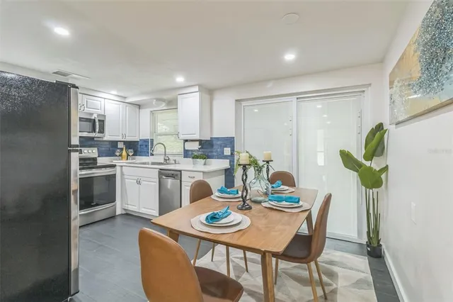 a kitchen with a refrigerator a stove a dining table and chairs