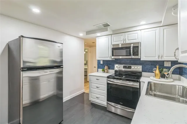a kitchen with white cabinets and stainless steel appliances