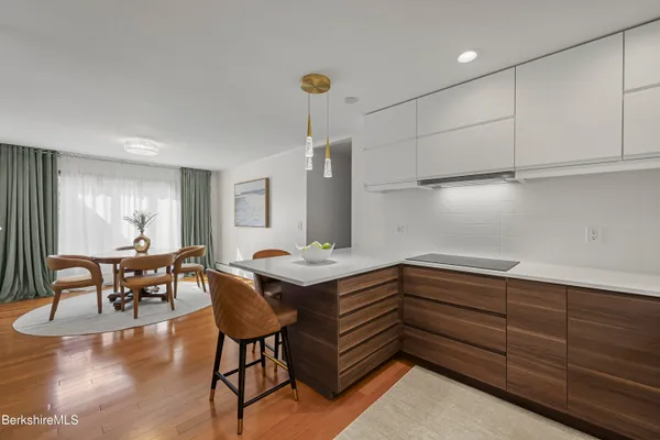 a kitchen with stainless steel appliances granite countertop a stove top oven a sink a dining table and chairs with wooden floor