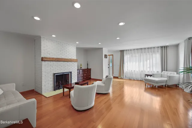 a kitchen with stainless steel appliances granite countertop a stove top oven a sink a dining table and chairs with wooden floor