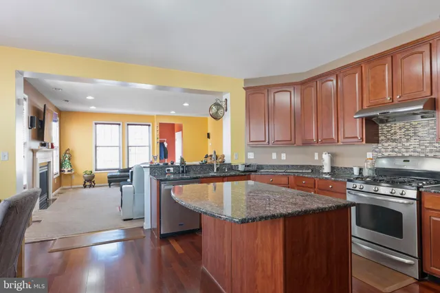 a kitchen with stainless steel appliances granite countertop a stove a sink dishwasher and microwave with wooden floor