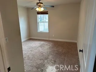 an empty room with windows and chandelier fan