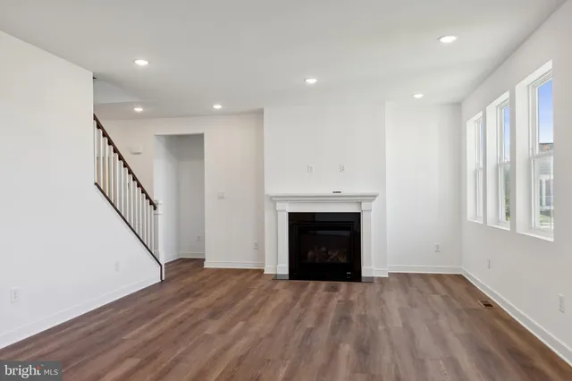 a view of an empty room with wooden floor fireplace and a window