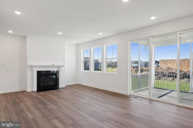 an empty room with wooden floor fireplace and windows