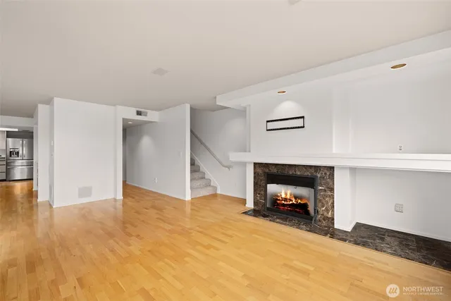 a view of an empty room with wooden floor and a fireplace