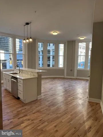 a large kitchen with kitchen island granite countertop a stove a sink a refrigerator and white cabinets with wooden floor