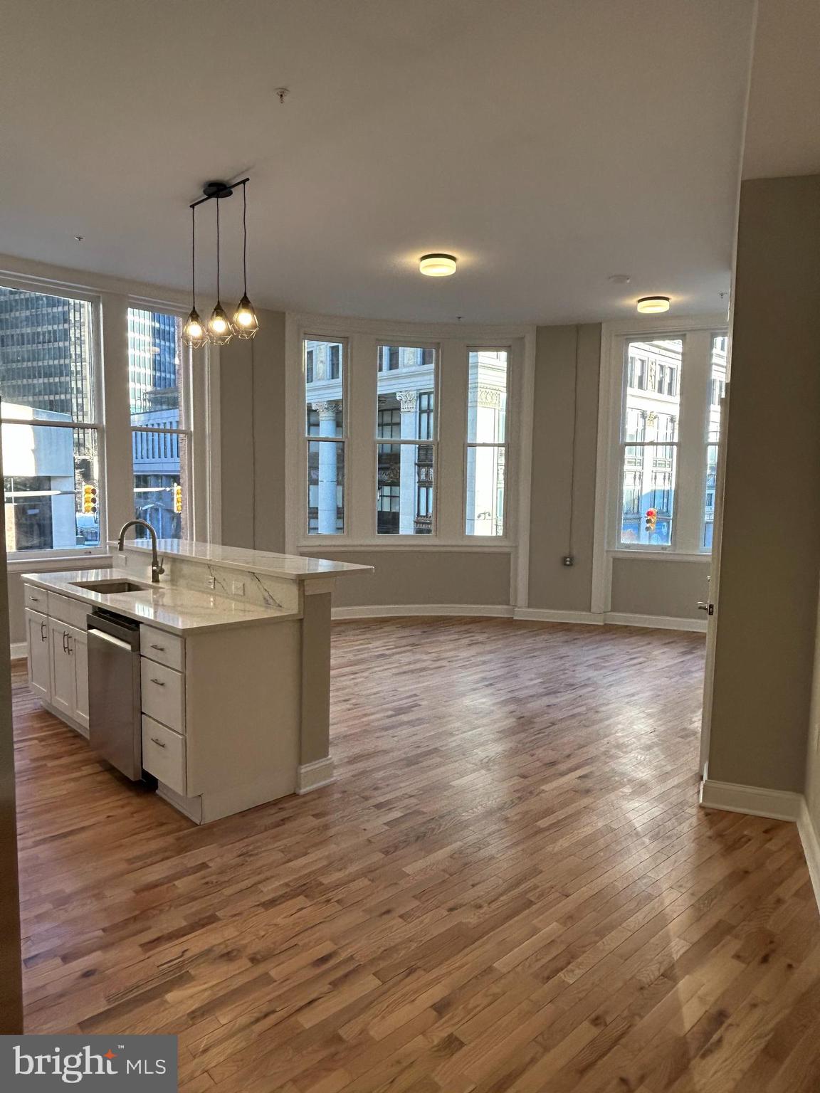 a large kitchen with kitchen island granite countertop a stove a sink a refrigerator and white cabinets with wooden floor