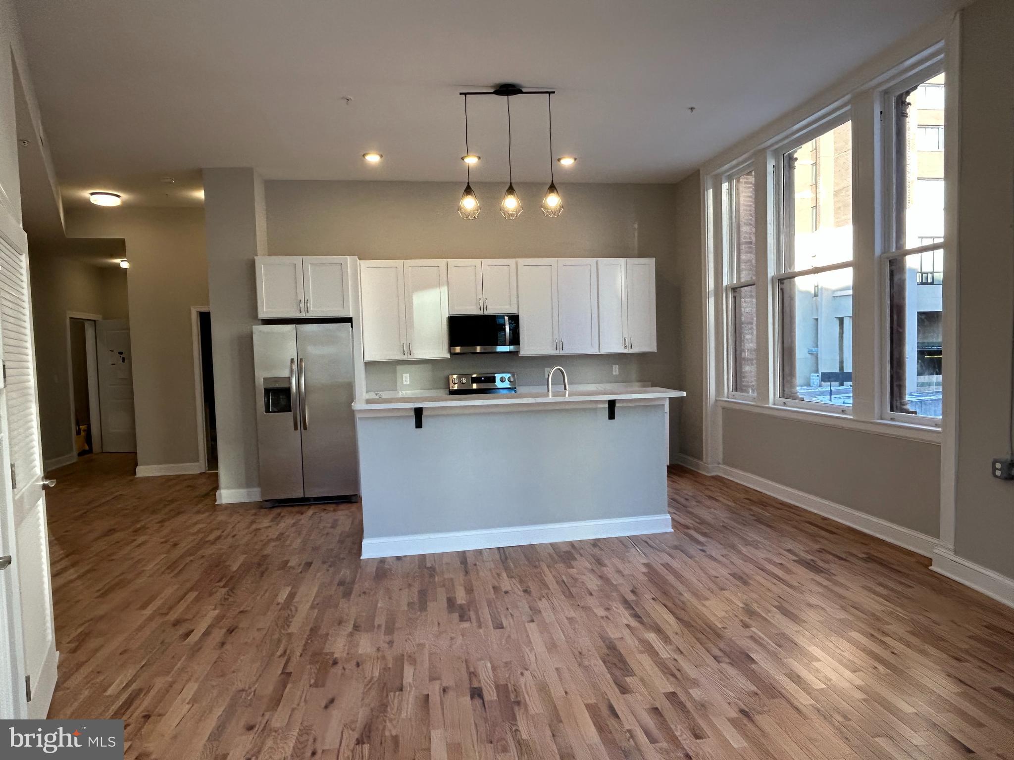 100 West Lexington Street, Unit 301 Baltimore, MD 21201 - Photo 12 of 30 a kitchen with stainless steel appliances granite countertop a refrigerator a sink dishwasher a stove and white countertops with wooden floor