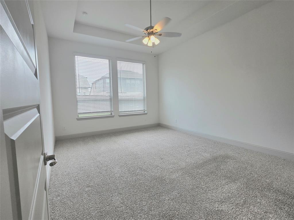 3208 Heathrow Road Mesquite, TX 75181 - Photo 7 of 21 This room features light-colored carpeting, white walls, and a tray ceiling with a ceiling fan