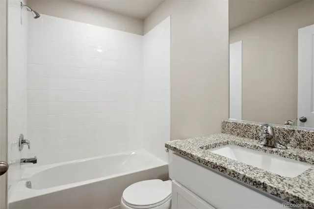 a bathroom with a granite countertop sink toilet and bathtub