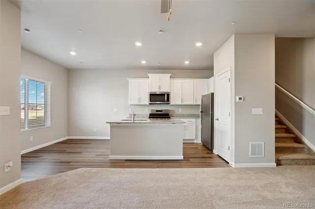 a view of kitchen with stainless steel appliances refrigerator stove microwave and cabinets